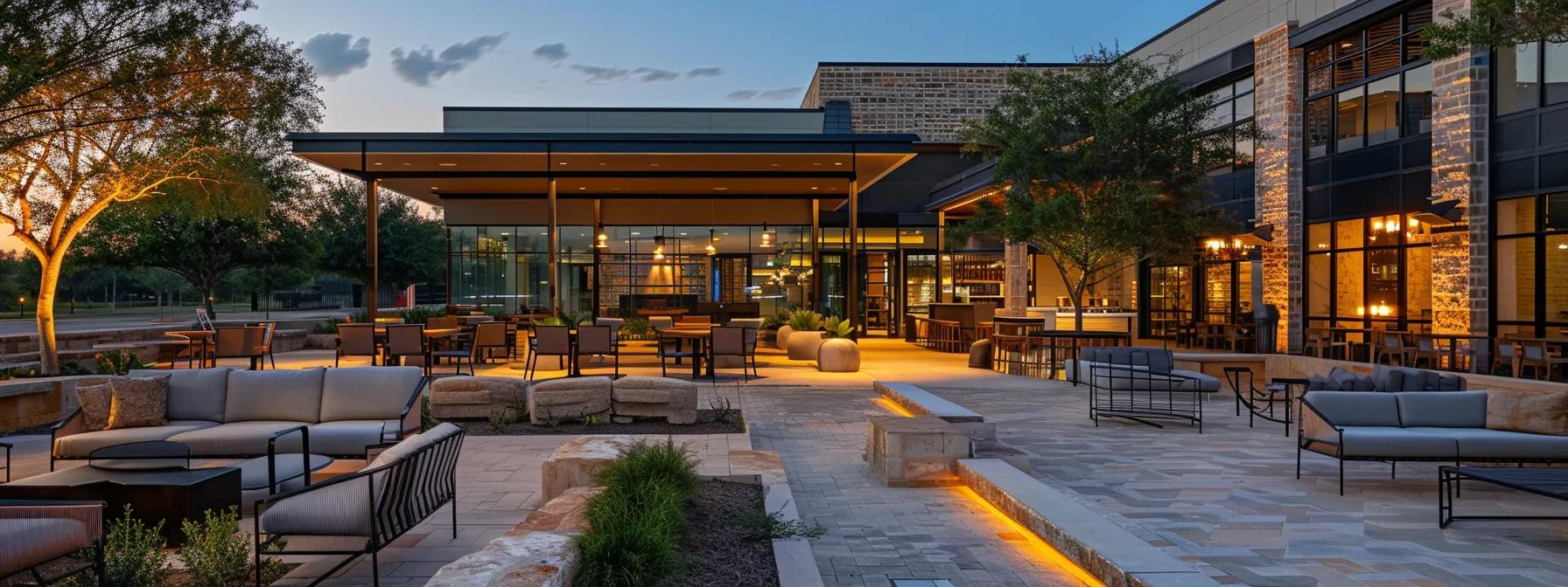 a modern outdoor living space in houston features a stylish patio with durable furniture, energy-efficient lighting casting a warm glow, and elegant landscaping that seamlessly integrates various functional zones for dining and relaxation.